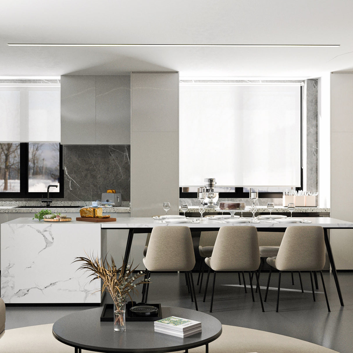 Modern kitchen features a marble island, beige chairs, set dining table with glassware, large windows with white blinds, and is brightly lit by Shallow Ceiling Recessed LED lighting Chanel Model Amara. A round coffee table holds dried flowers and books in the foreground.