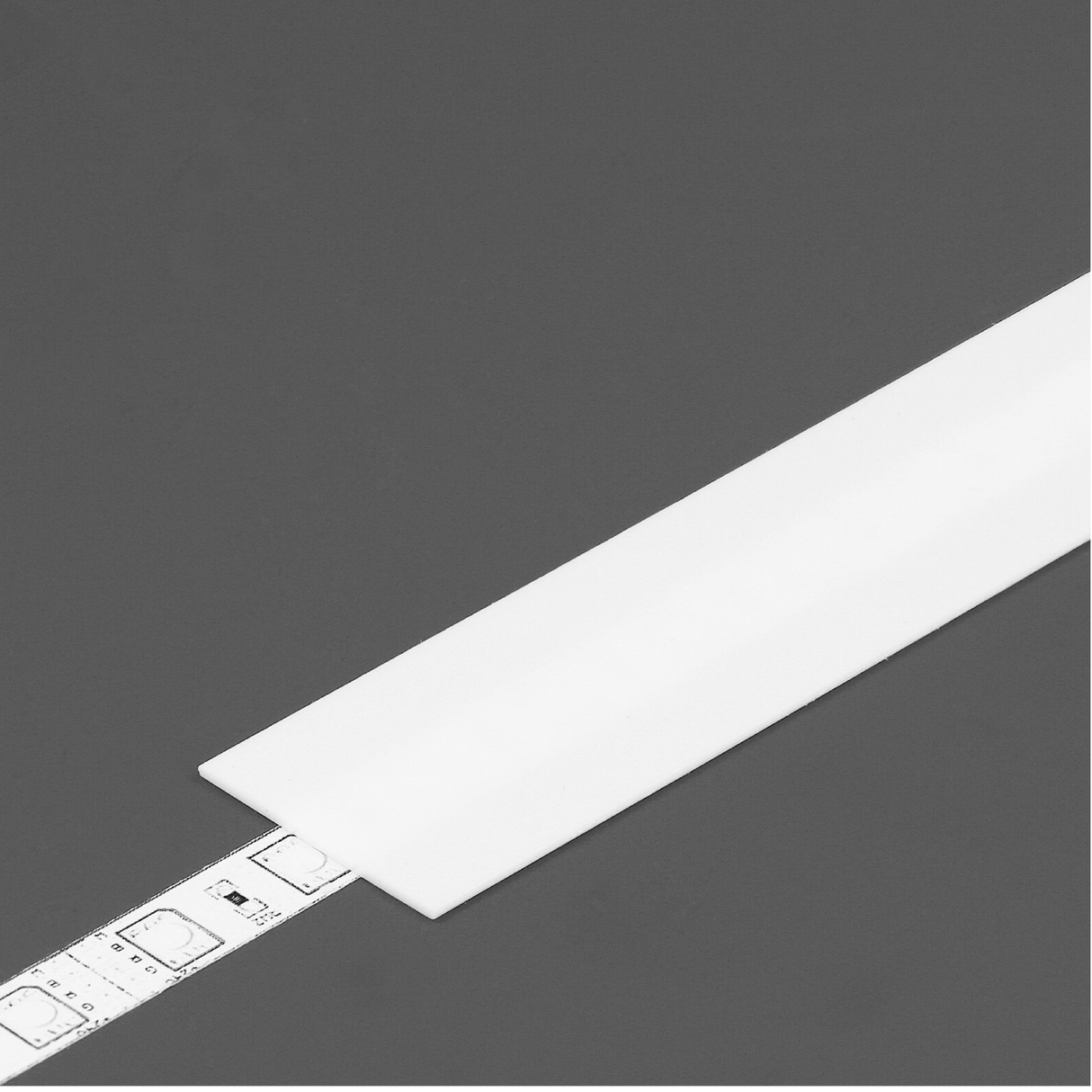 The LED Channel Cover ~ A6 Slide, a white rectangular cover, is shown partially placed over a silver measuring tape with black markings on a plain gray background.