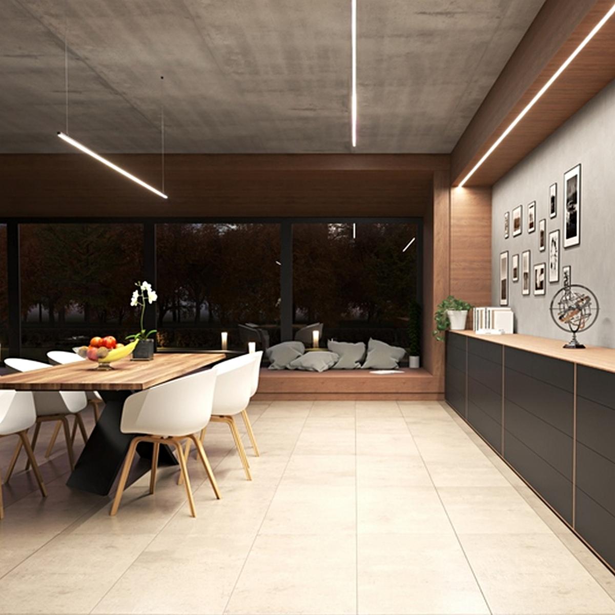 A modern dining room features a large wooden table, white chairs, and minimalist decor. Soft light from the Cozy12 Small Anti-Glare Lighting LED Channel highlights the sideboard, while large windows reveal trees and neutral-toned flooring.