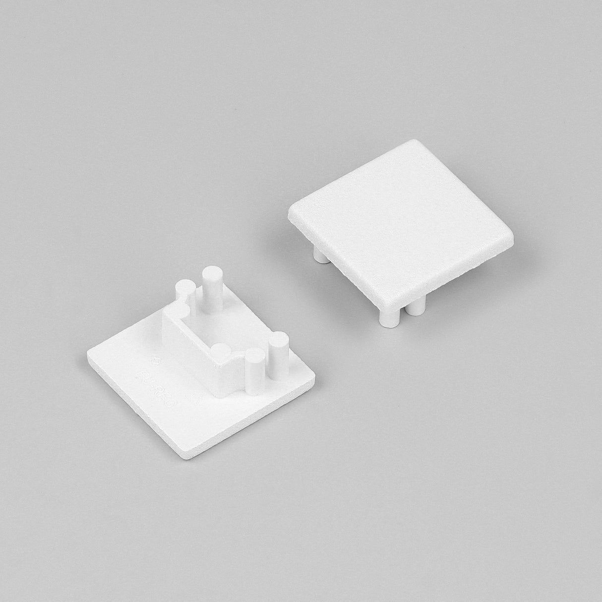 Two small, white, square plastic End Caps for Cozy12 Profile are shown on a plain gray background. Each has protruding pegs on one side, indicating they are designed to fit together as part of the Cozy12 lighting fixture.
