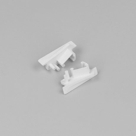 Two small, white End Caps for Diagonal10 Profile, featuring angular shapes and protruding pegs, are displayed on a plain light gray background.