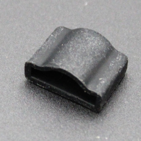 Close-up of the Endcap for Optimum Black Neon Max—a small, black, rectangular plastic clip with a curved top—resting on a dark surface. Ideal for securely attaching neon accessories.