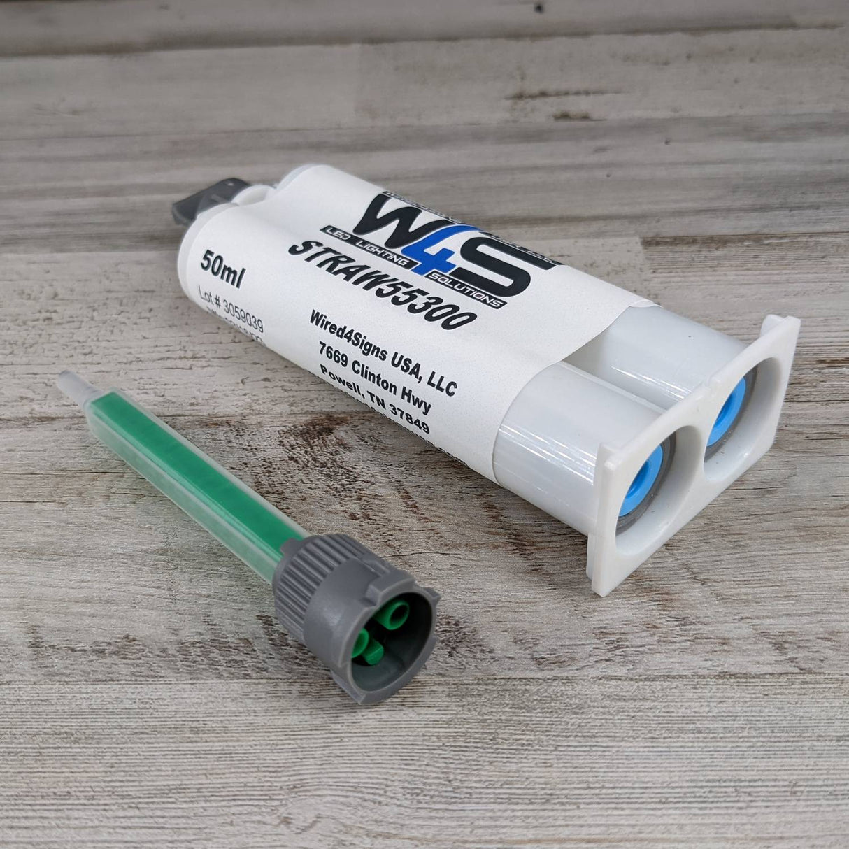 A 50ml dual-chamber Cream 2-part Methacrylate Adhesive ~ W4S 55300 (1:1 Mix B-System) cartridge with a white label and green mixing nozzle, for bonding applications, displayed on a wooden surface with product and company info visible.