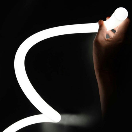 A hand holds the Flexible White LED Neon Tube ~ Neon 360 Series, showcasing its smooth, glowing 360-degree illumination as it curves gracefully against a dark background.