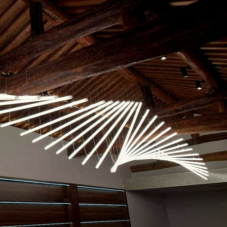 A Flexible White LED Neon Tube from the Neon 360 Series forms a spiral chandelier beneath exposed wooden beams, providing all-around illumination while natural light enters through horizontal windows on the left.
