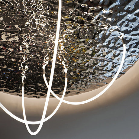 Flexible White LED Neon Tube ~ Neon 360 Series fixtures hang before a rippled, reflective metallic ceiling, producing an abstract, modern look with dynamic 360-degree illumination and striking distorted reflections.