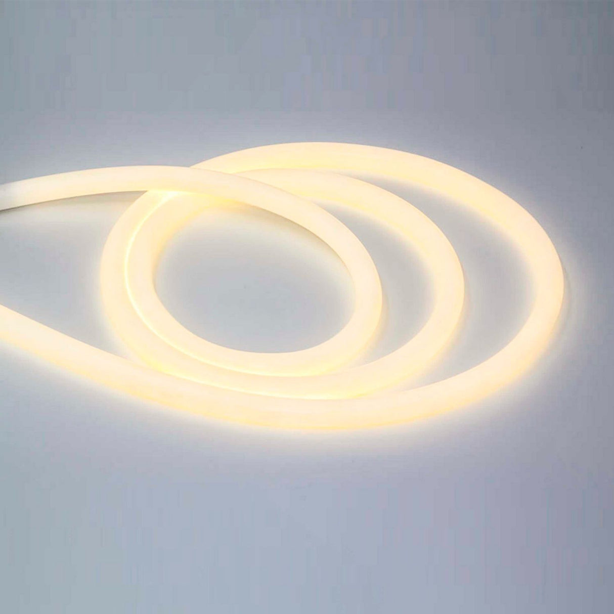 The Flexible White LED Neon Tube ~ Neon 360 Series creates loose loops on a smooth, light surface, glowing softly in warm white with full 360-degree illumination.
