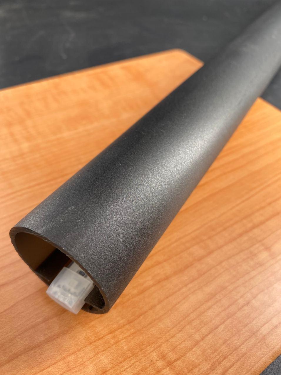 The Bright RGB IP68 LED Strip (24V) ~ Verbena Series is shown: a black cylindrical tube with a network cable connector inside, positioned diagonally on light wood, resembling sleek housings for color changing LED tape installs.