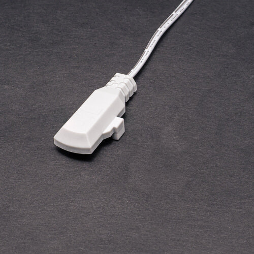 A Power Track Twist Plug Connector with a white cable and rectangular connector lies on a plain dark surface.