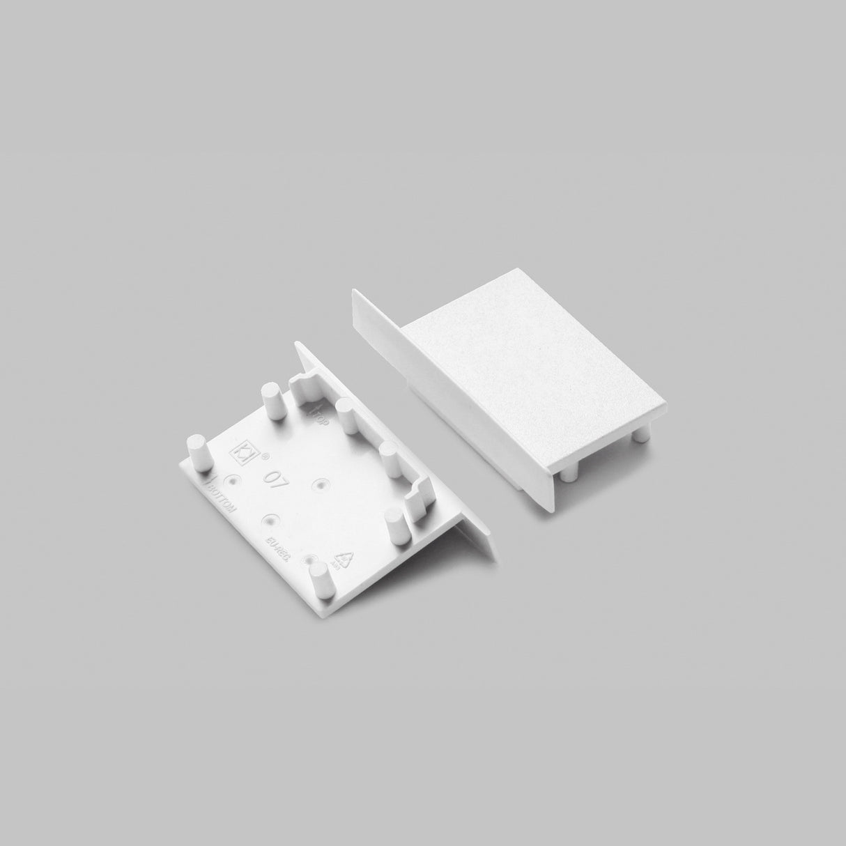 Two white End Caps for Vario30-07 profile are shown on a gray background—one displays its pegs and slots, the other its flat surface. These plastic caps are ideal for lighting fixture setups.