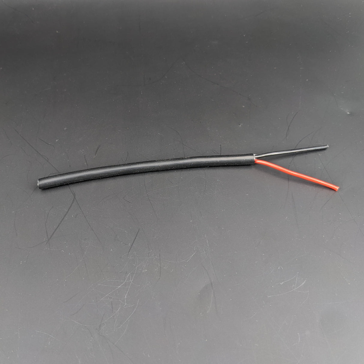 A short length of 2-Core 18 AWG Silicone Electrical Wire with red and black wires exposed against a solid dark background.