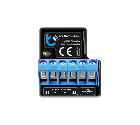The shutterBoxDC by Blebox is a black and blue wireless controller for DC roller blinds/shutters (12-24V DC, 5A max), featuring six terminal slots and remote smart control. Product name is labeled as Smart Wireless Roller Blind/Shutter Controller.