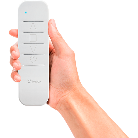 A hand holds the sRemote by Blebox, a white single channel battery-operated remote with up arrow, square, down arrow, and heart buttons, plus a blue indicator light and Blebox logo. Compatible with μWiFi-enabled BleBox devices.