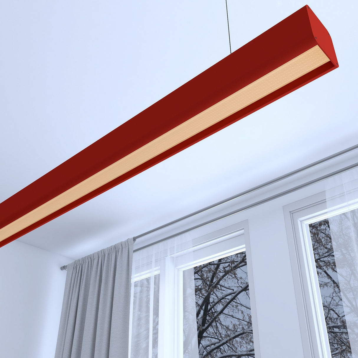 A Modern Pendant Strip Light Channel ~ Model Antonio in red, with a rectangular design, hangs from the ceiling of a bright room with large windows, gray curtains, and a view of bare tree branches outside.