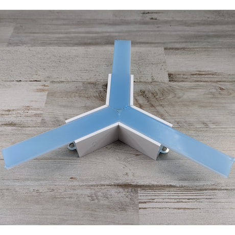 Three white and blue rectangular bars, forming the 3-Arm Y-Connector for Linea20 Profile, are joined at the center and rest on a light wood surface.