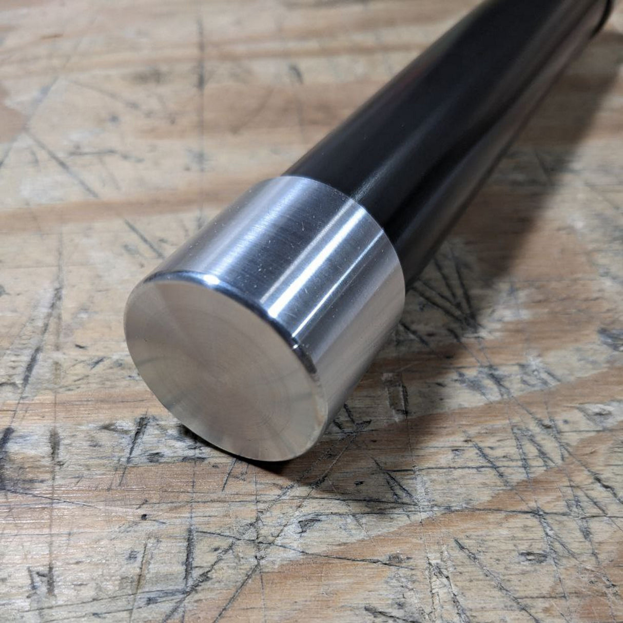 An Aluminum End Cover for 1.50 Round Profiles with a sleek, modern finish sits on a scratched wooden surface.