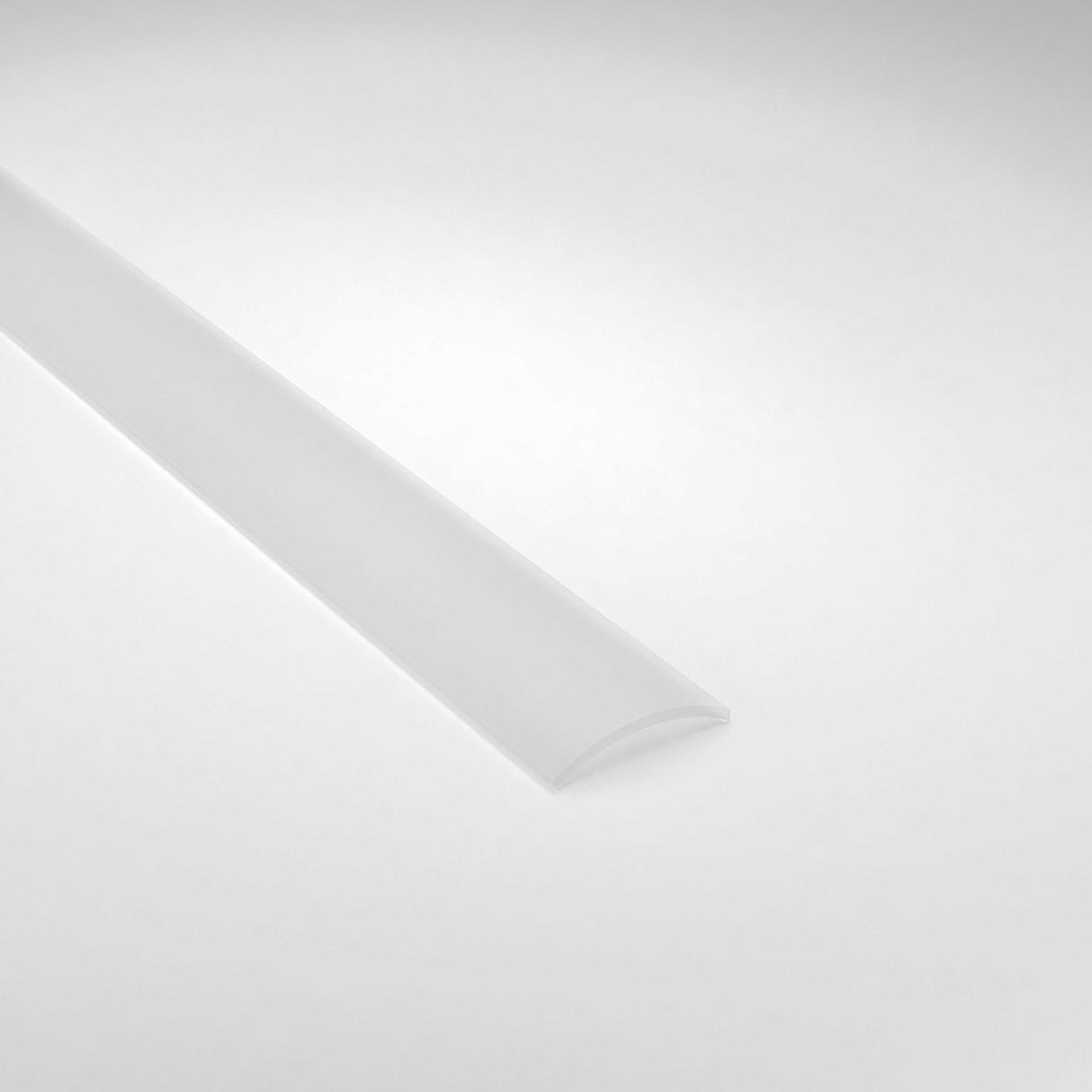 A semi-transparent Diffuser for Ricardo Profile made of polycarbonate rests diagonally on a light gray surface. Tapered at the back, it casts a subtle shadow while showcasing its curved design.