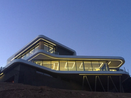 Modern multi-level building at dusk featuring integrated architectural LED lighting along the curved exterior edges