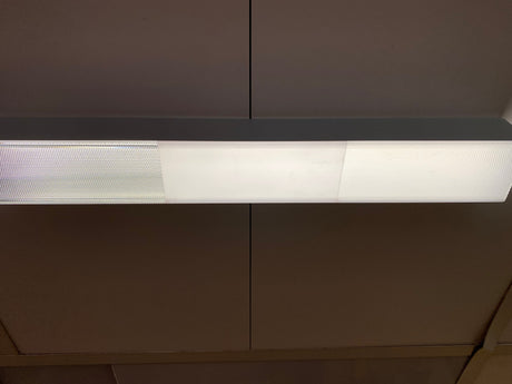 Ceiling-mounted LED fixture displaying a side-by-side comparison of different PL55 diffuser covers with varying light diffusion patterns