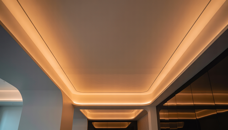 A modern interior room with LED cove lighting highlighting the ceiling, creating a warm glow and showcasing contemporary furniture.