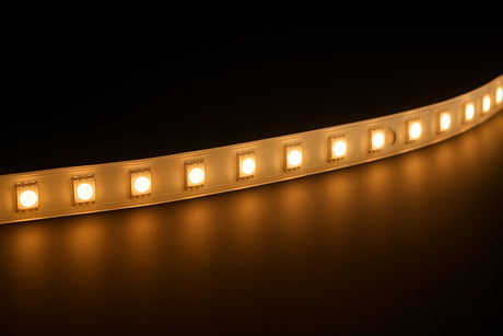 Warm white LED strip on a dark background shining onto a reflective surface.
