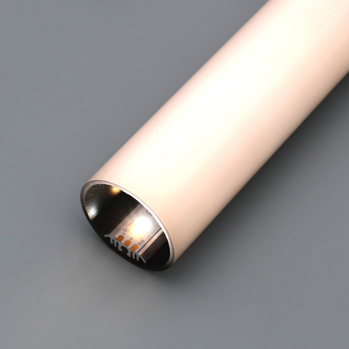 A close-up of the 1.50 Polycarbonate LED Tube, Model Sierra38, a cylindrical metallic object with one end glowing, positioned on a gray surface.