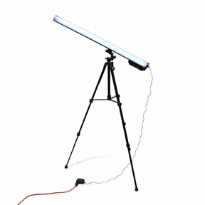 A Portable Long Range Casambi RGBW Tube Light is mounted diagonally on a black tripod stand, plugged in with a power cable and orange extension cord on the floor, creating an ideal wireless stage lighting setup against a white background.