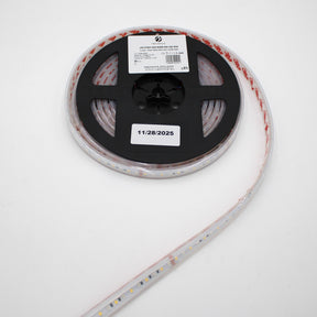 A roll of Low-Power RGBW IP67 Waterproof LED Strip (24V) ~ Iris Series is shown on a black plastic spool with a white label dated 11/28/2025, with the LED strip extending from the reel against a white background.