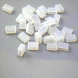 Several small, translucent Waterproof End Cap Covers for IP67/IP68 LED Strips are scattered on a gray surface, perfect for sealing and protecting strip light ends.