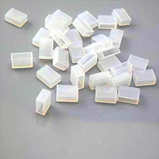Several small, translucent Waterproof End Cap Covers for IP67/IP68 LED Strips are scattered on a gray surface, perfect for sealing and protecting strip light ends.