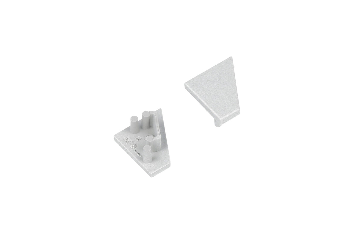 Two small, light gray, triangular plastic End Caps for the Corner10.v2 Profile—one oriented upward to reveal a smooth surface, the other inverted to display pegs and notches on the underside—sit against a white background. These components are designed specifically for use with the Corner10.v2 Profile lighting fixture, providing a clean and secure finish.