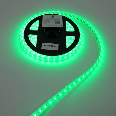 A spool of Low-Power RGBW IP67 Waterproof LED Strip (24V) ~ Iris Series glows brightly on a white surface, with a label showing a barcode and date attached to the reel.