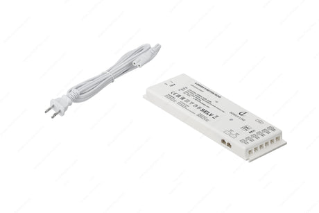 A white two-prong power cable is beside a rectangular white Dimmable Plug-In LED Driver (24V) from the X-Driver D-Motion Series, which has labeled terminals and technical details printed on its surface.