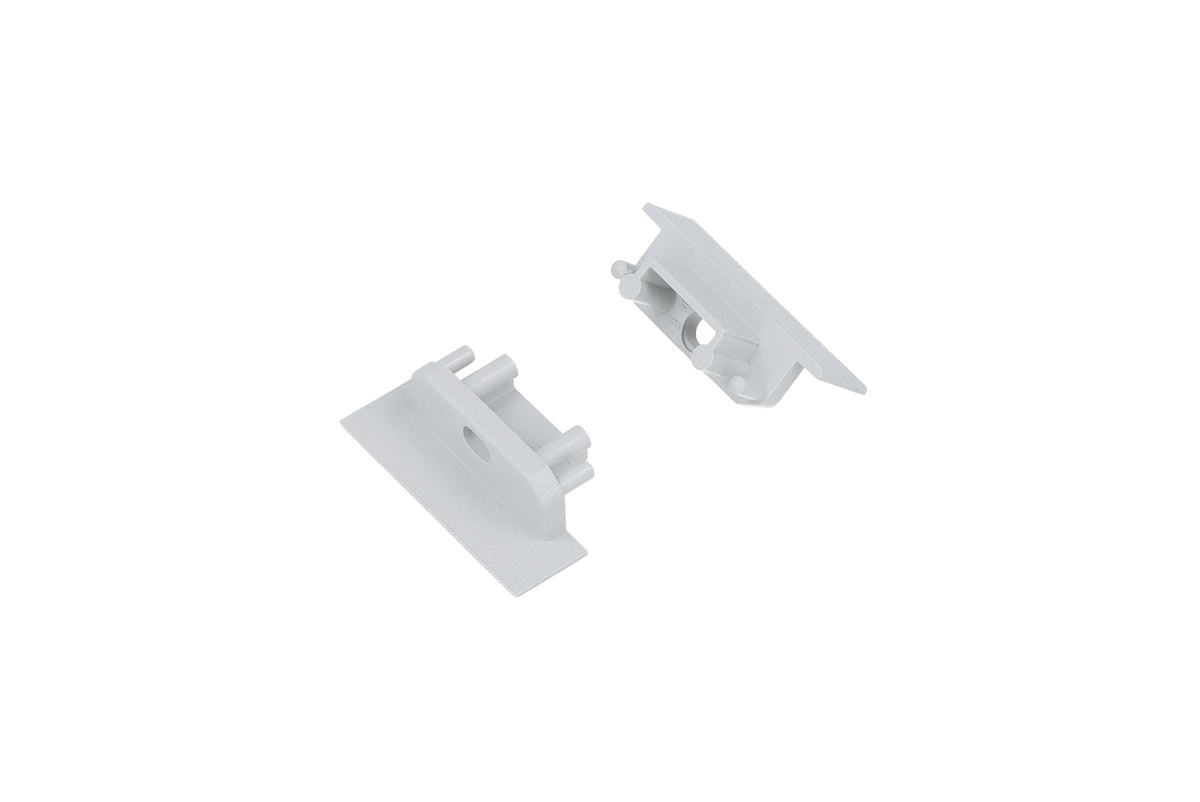 Two small, white plastic End Caps for the Groove10.v2 Profile—each with a flat rectangular base and cylindrical pegs and holes designed for mounting or connecting—are displayed on a plain white background.