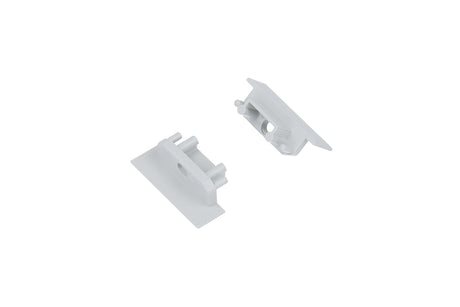 Two small, white plastic End Caps for the Groove10.v2 Profile—each with a flat rectangular base and cylindrical pegs and holes designed for mounting or connecting—are displayed on a plain white background.