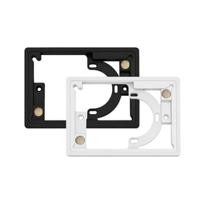 Two rectangular plastic framePanelM wall mount frames for controlPanelM screens by BleBox, one black and one white, are shown overlapping. Each frame features circular and rectangular cutouts, screw holes, and small metal contact points on their surfaces.