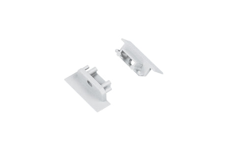 Two small, rectangular, silver metal End Caps for Groove10.v2 Profile with raised edges and cylindrical posts are positioned on a white background facing each other.