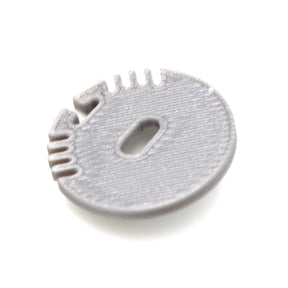 A gray, round plastic End Cap for Alu Round Profile with ridges, a central oval cable hole, and several small edge notches, shown on a white background.