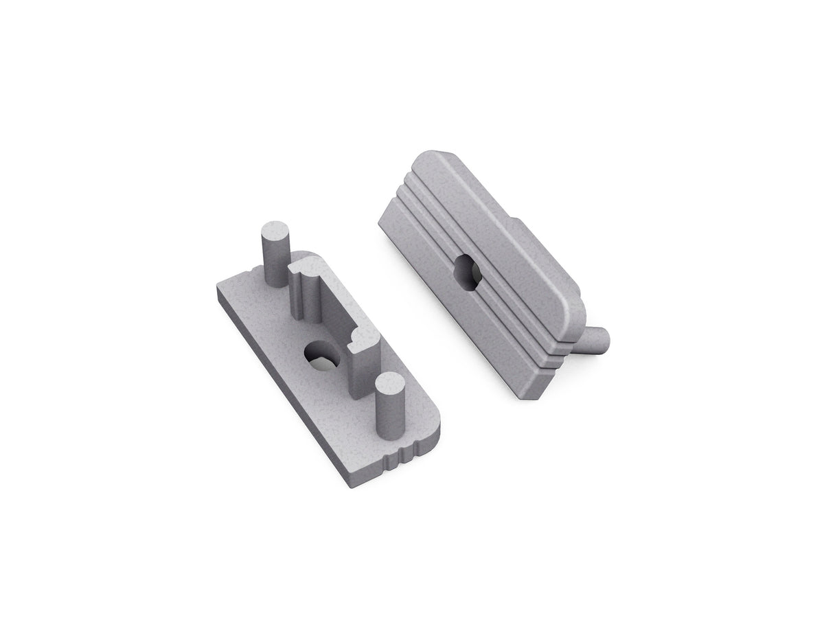 Two gray End Caps for Surface10 Profile, featuring interlocking ridged surfaces and cylindrical pegs, are displayed on a white background—ideal essential accessories for LED channel installations.