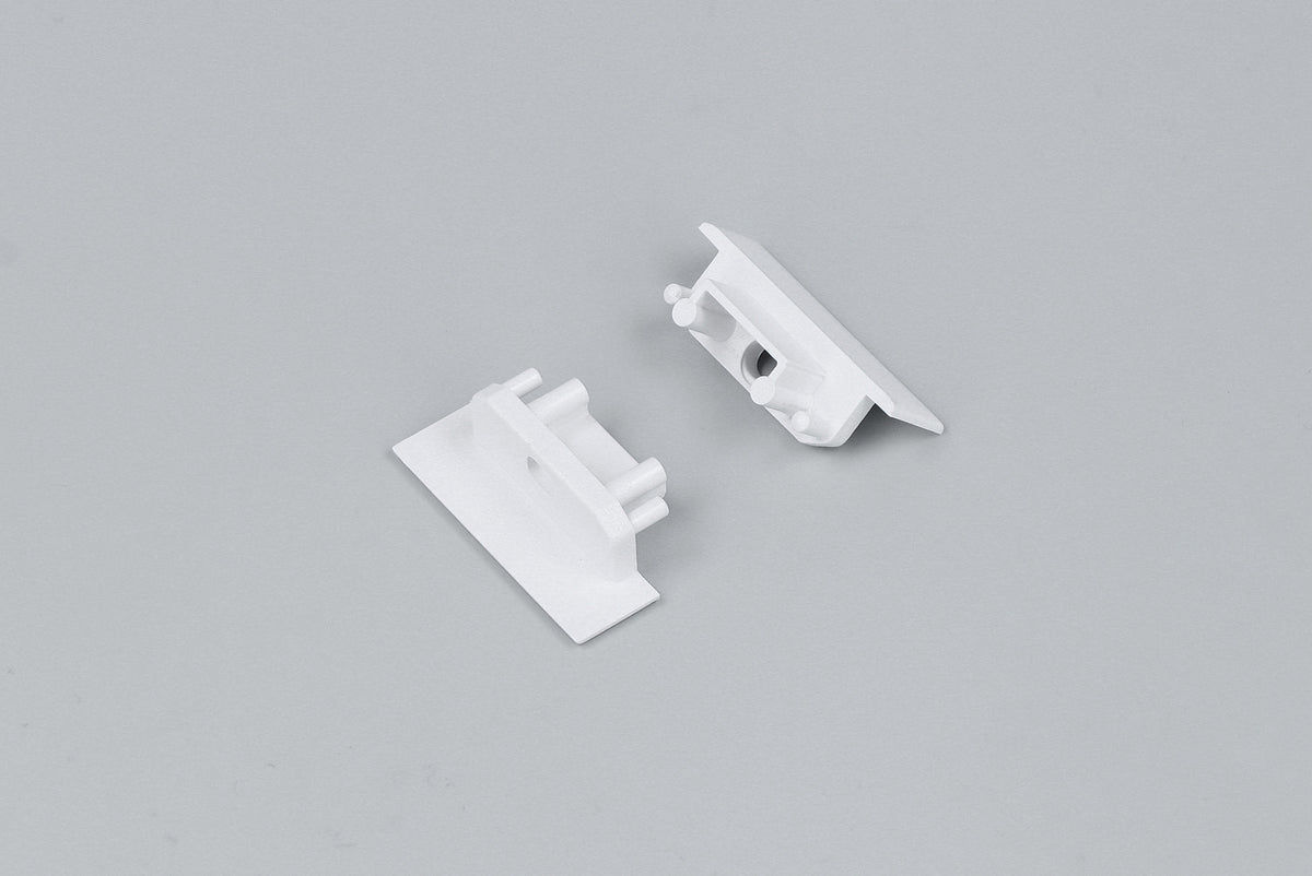 Two small white plastic End Caps for the Groove10.v2 Profile lighting fixture, each featuring a flat rectangular base and interlocking parts, are displayed on a plain light gray background.