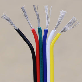 Six multicolored wires—black, red, green, blue, white, and yellow—stand upright with exposed silver strands at the top against a plain beige background. This 6-Core 18/20 AWG PVC Flat Ribbon Wire for RGB+TW LED Strip is perfect for connecting RGB+CCT or RGBWW LED strip cables in various lighting projects.
