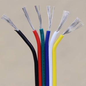 Six upright wires from the 6-Core 18 AWG PVC Flat Ribbon Wire for RGB+TW LED Strip—black, red, green, blue, white, and yellow—show exposed silver strands against a plain beige background.