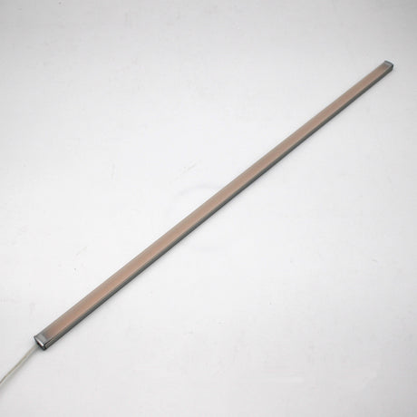 A slim, rectangular White Universal Surface-mount LED Lighting Fixture ~ Begton12 Series with a beige cover is placed diagonally on a plain white background. This dotless light bar features a visible power cord, ideal for under-cabinet lighting.