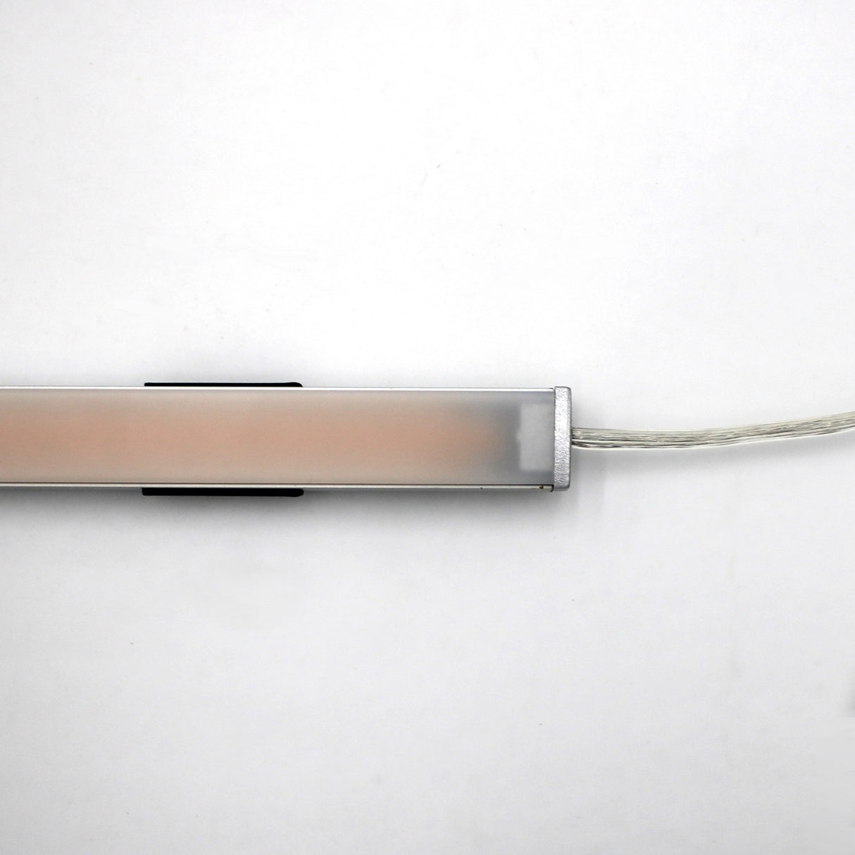 The White Universal Surface-mount LED Lighting Fixture ~ Begton12 Series is a rectangular, dotless LED with a frosted cover, mounted horizontally on a white wall with a transparent power cord extending from the right side.