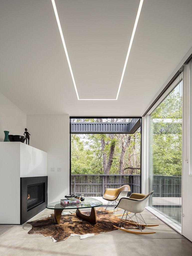 Bright minimalist sitting area with linear cool white LED strip lights recessed into the ceiling, enhancing architectural lines and natural daylight.