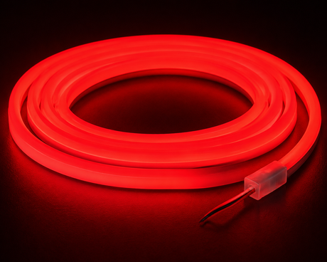 The Color IP44/IP66 Neon Flexible LED Light Line (24V) ~ Flex Ultra Slim Series emits a vibrant red glow while coiled, standing out against a dark backdrop, with two exposed wires visible at one end.