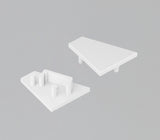 Two white, triangular End Caps for the Corner12.v2 Profile are displayed on a gray background. One has a smooth surface with two pegs below, and the other features three pegs plus a rectangular slot for a lighting fixture.