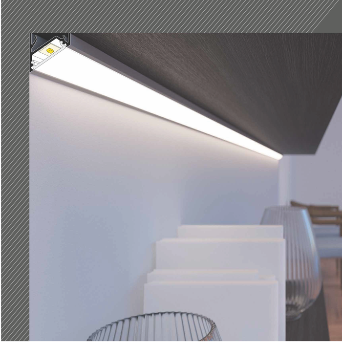 A Surface Mount Corner LED Channel (Model Corner16) installed under a dark shelf casts light onto the wall and white rectangular items below. Two glass bowls sit on the surface, with a wooden chair visible in the background.