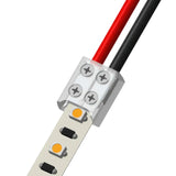 Close-up of the 2-Pin Solderless White LED Strip Screw Connector (10mm) ~ EnoLED Series, joining a red and black wire to an LED strip with visible screw terminals securing both the wires and the strip.