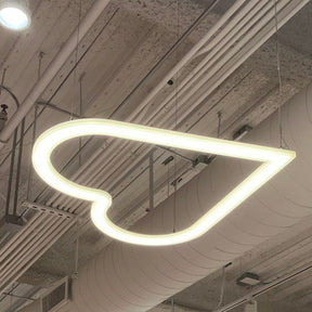 The Heart Shaped Light Fixture brings a warm glow to any space, hanging elegantly from an industrial-style ceiling with exposed pipes and ducts for a modern yet charming look.